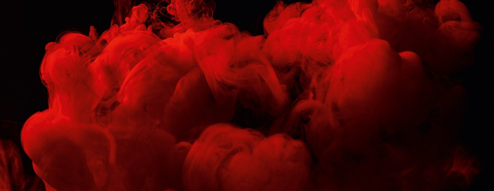 Rote Rauchwolken vor schwarzem Grund