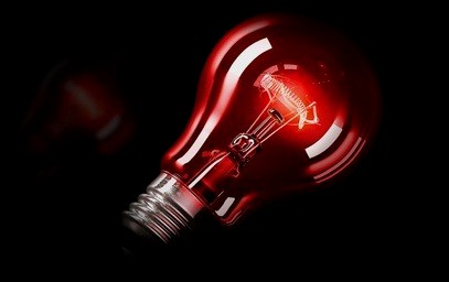 Rot leuchtende Glühlampe vor schwarzem Grund