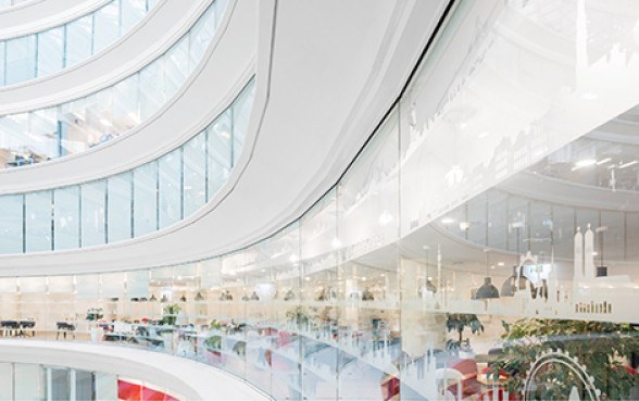 Helles Atrium mit geschwungenen Galerien und Glasfronten